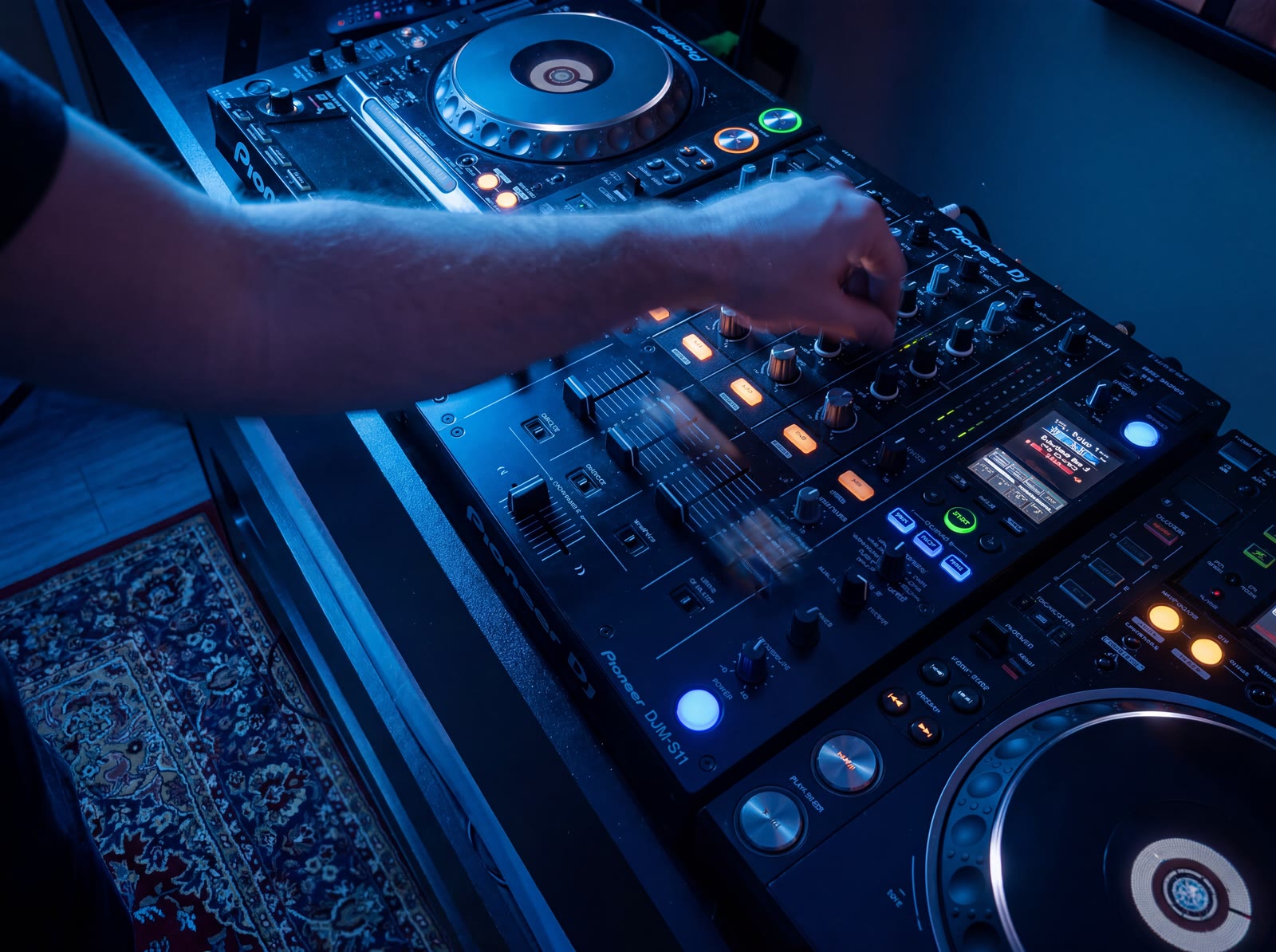 Close-up van de handen van een dj op de Pioneer-mixer in een blauwverlichte Temple Studios-booth