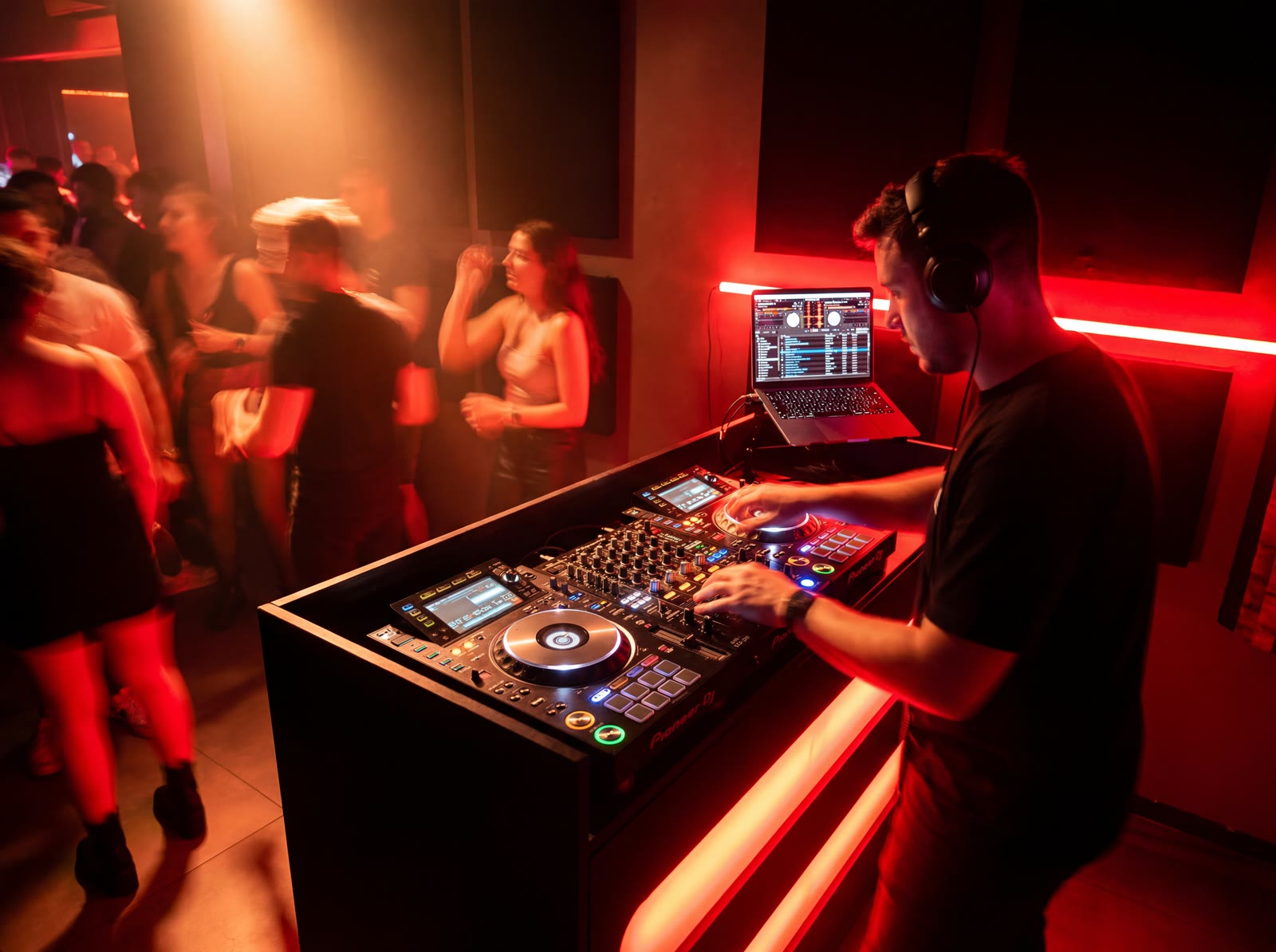 Een dj die speelt voor een dansend publiek in een roodverlichte Temple Studios-booth